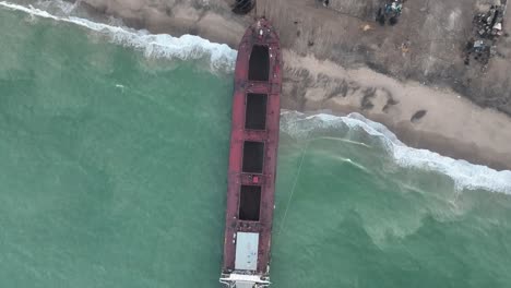 Aerial-drone-top-down-shot-over-an-old-ship-beached-in-a-cruise-ship-yard-at-Gaddani,-Pakistan-at-daytime