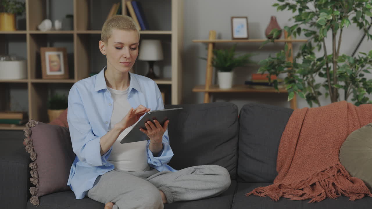 Pregnant woman using a tablet on the sofa