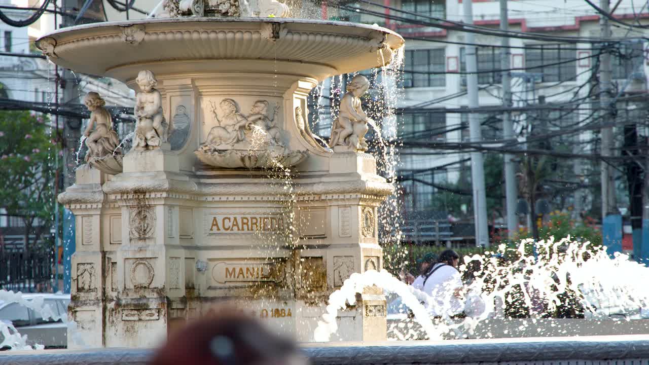 Inquadratura media fissa della storica fontana in pietra Carriedo con spruzzi d'acqua a Manila.