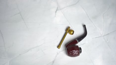 man putting tobacco smoking pipes on table