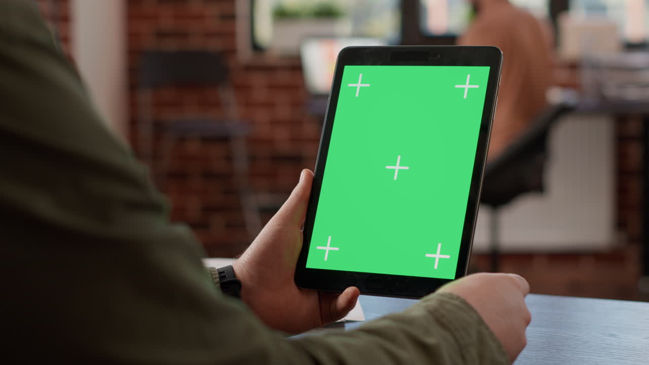 Startup employee looking at digital tablet with greenscreen