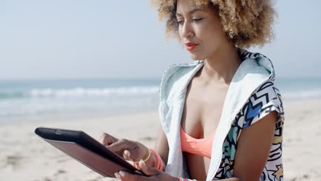 chica afroamericana usando una tableta en la playa