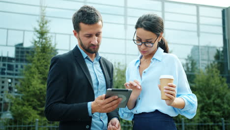 businesspeople discussing on a tablet outdoors