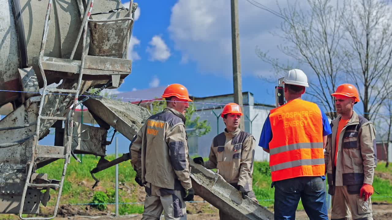 Group of workers installing metal base. Industrial machine with cement. Workers put metal construction before installing solar panels on the ground.