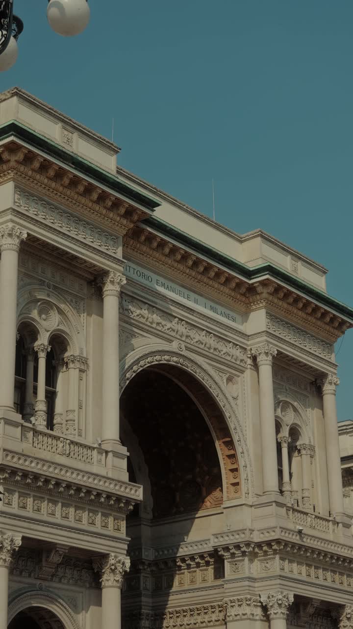 Vista di un arco ornato e di un lampione classico vicino al Duomo di Milano, che evidenzia l'architettura storica del centro di Milano.