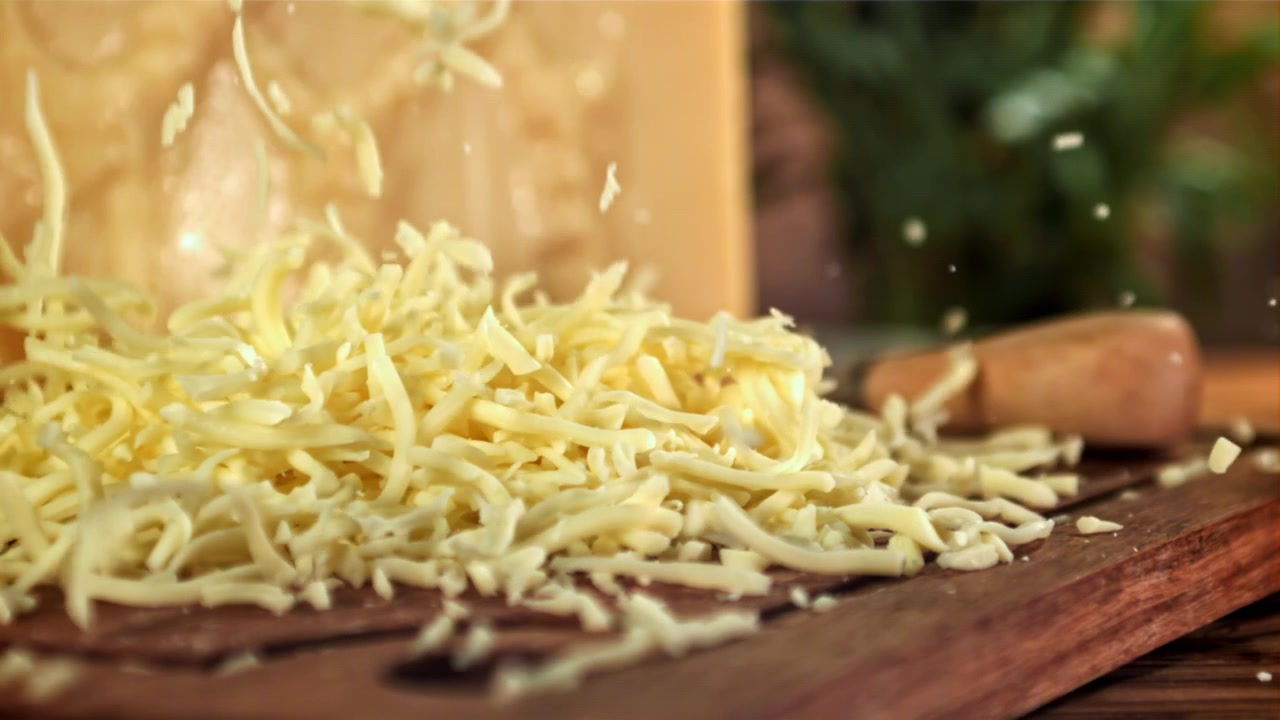Formaggio fresco grattugiato che cade su un tagliere di legno