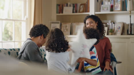 happy family having pillow fight mother and father enjoying playing with children at home having fun together on weekend