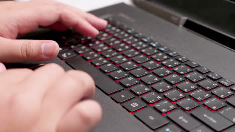 close up of a pair of hands scrolling the internet and typing some words using the electronic keyboard of a laptop computer