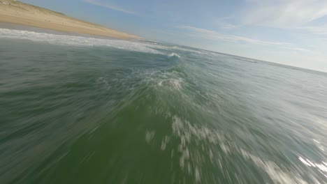 Drohne-Fliegt-Tief-über-Der-Meeresoberfläche-Entlang-Des-Strandes-Von-Soustons,-Frankreich