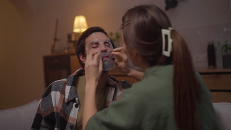 pareja aplicando máscaras faciales en el hogar