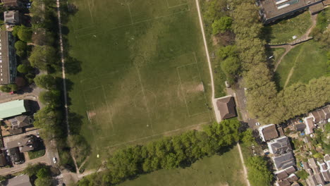 green local football yards with white lines in small town, aerial top down view