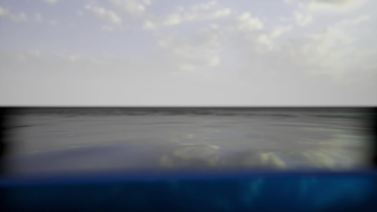 Calm ocean water reflecting clouds under a serene sky at midday