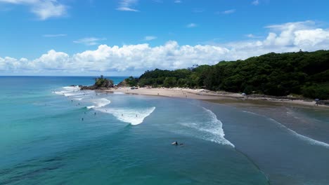 stunning 4k aerial drone video capturing the pass beach in byron bay, australia. turquoise waters, golden sandy shores, and surfers riding the waves at one of the most iconic surf spots in australia.