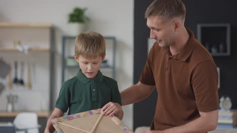 father and son making a kite together at home