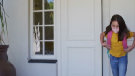 Caucasian-girl-wearing-face-mask-with-backpack-standing-outside-the-house