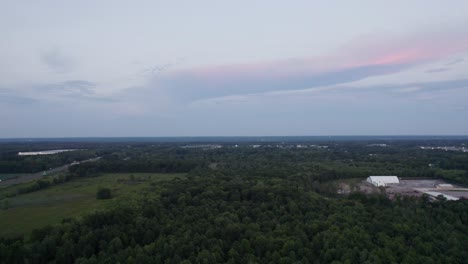 Luftdrohne-Vorwärts-Bewegender-Schuss-über-Den-üppigen-Grünen-Wald-Neben-Einer-Straße-Während-Der-Abendzeit-Nach-Sonnenuntergang