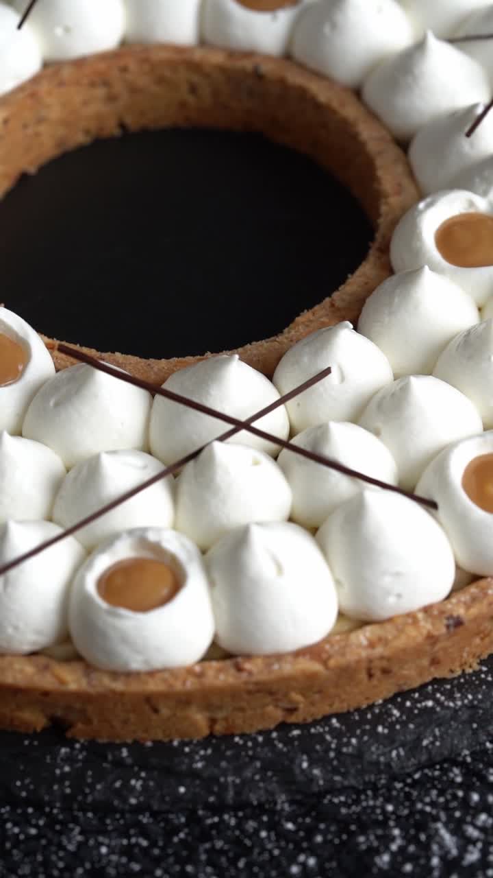 A chief decorates a cake of caramel with chocolate and cream, high angle shot
