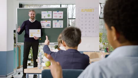 profesor enseña a un grupo de estudiantes multiétnicos las palabras 'feliz' y 'triste' en el aula de inglés 2