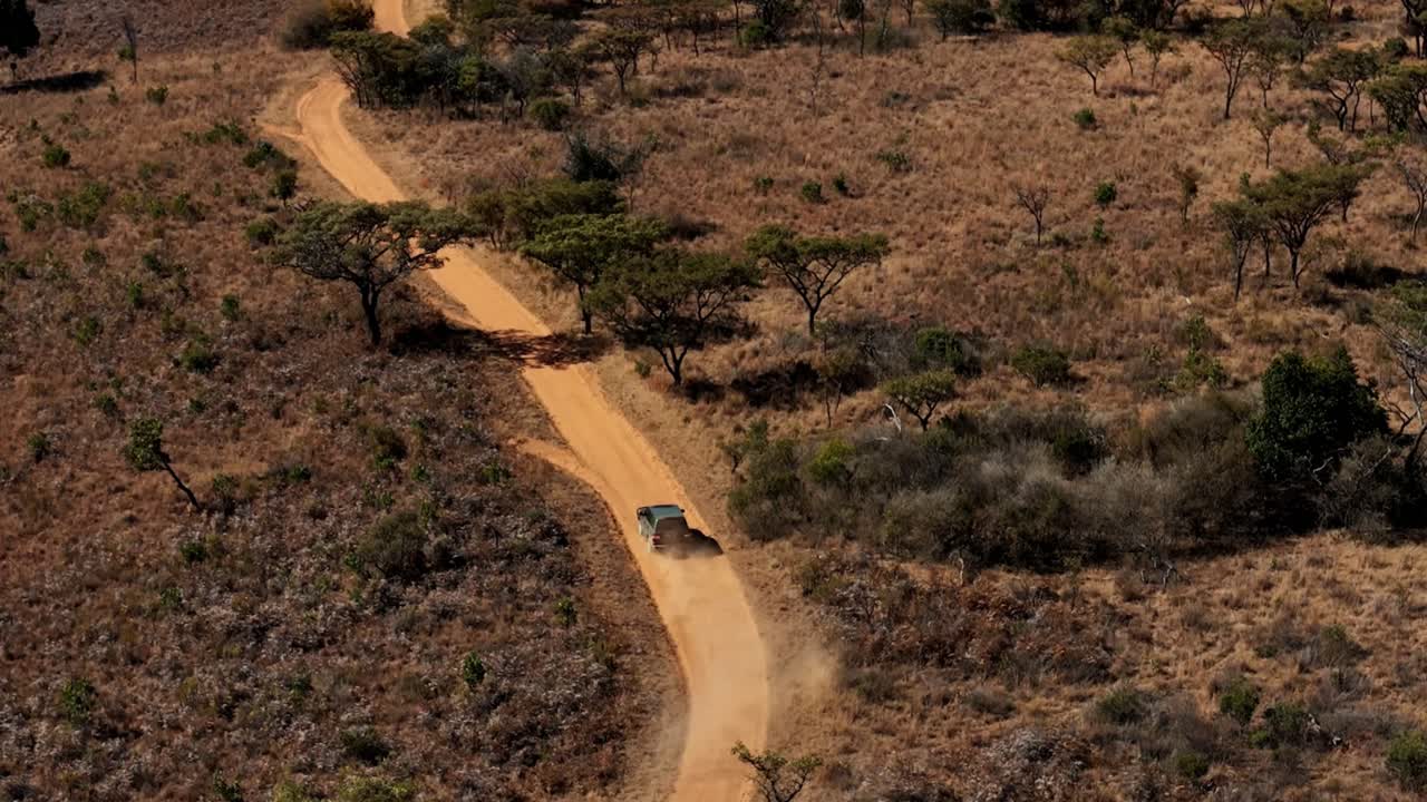 vehículo suv conduciendo en un camino de tierra seca, paisaje de invierno en sudáfrica, capturando vistas serenas de vegetación seca y rastro de polvo en cámara lenta