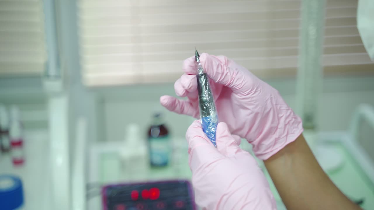 beautician is holding in her hands professional cosmetic tool for permanent makeup of eye. Needle for using in the procedure permanent makeup