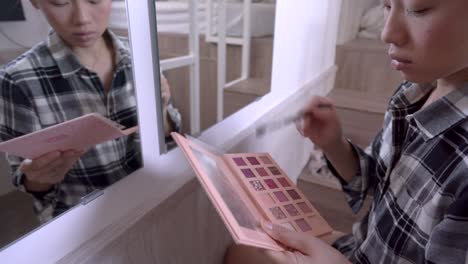 mujer asiática haciendo maquillaje en casa