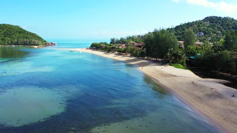aguas tranquilas y claras de la laguna con hermosos diseños de corales y algas cerca de la playa de arena en una isla tropical con vegetación exuberante
