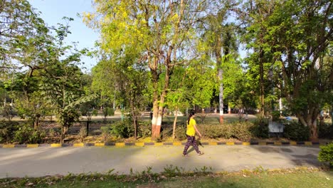 Steady-shot-of-girl-walking-in-park-with-trees-in-the-background-on-a-sunny-morning