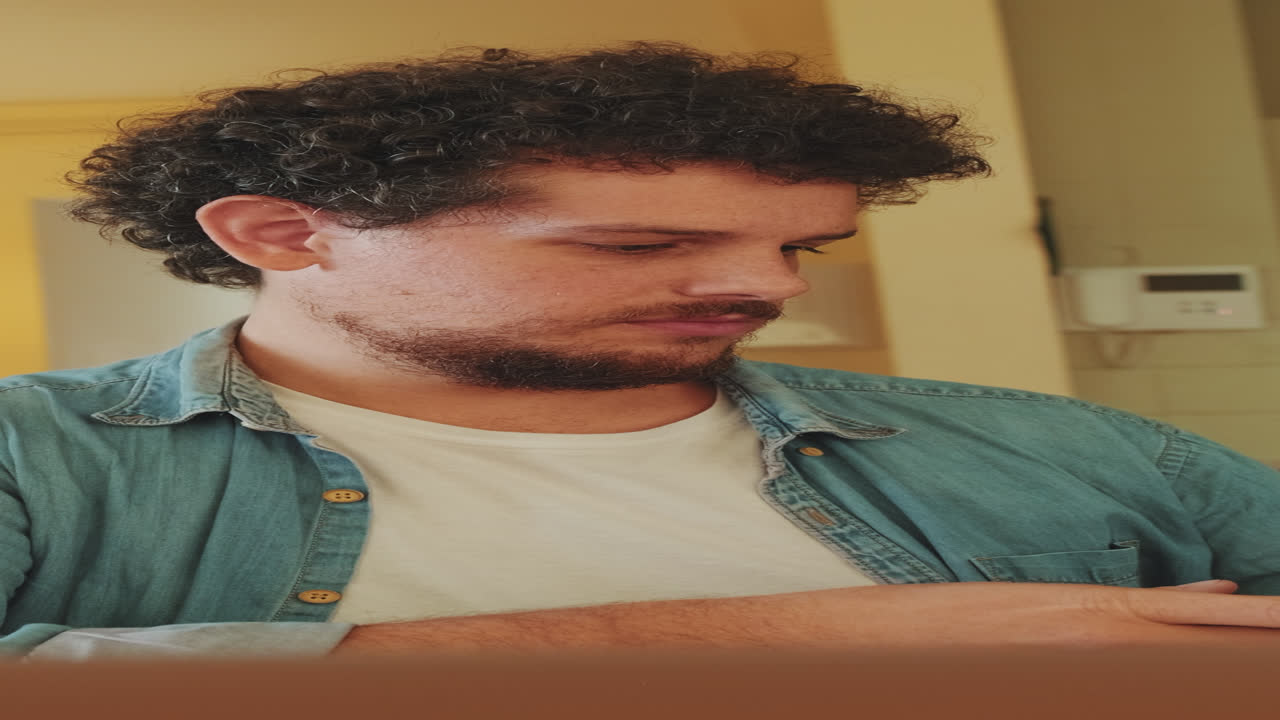 Man with curly hair wearing a denim shirt