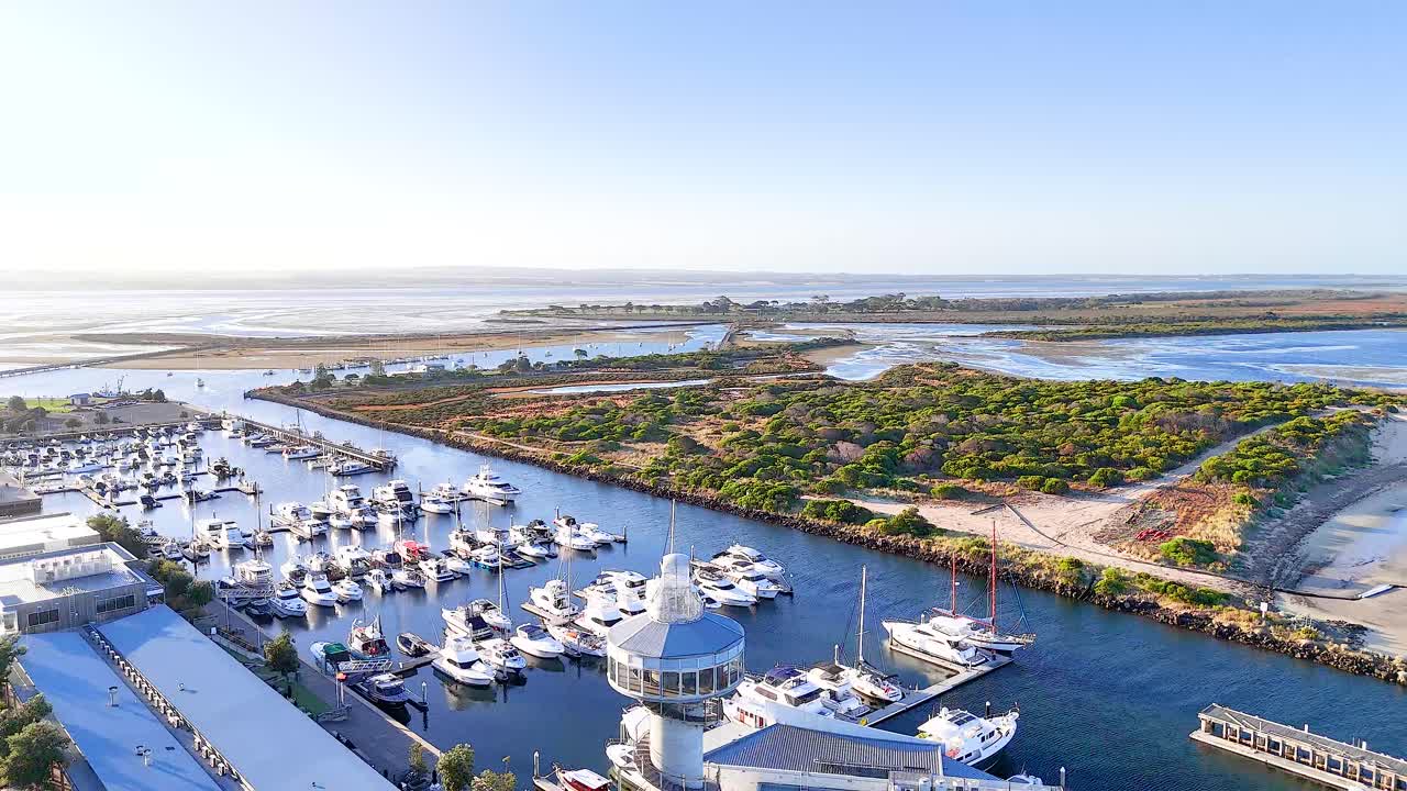 Aerial footage captures Queenscliff Marina with boats, lighthouse, and scenic coastline under clear skies in Bellarine, Victoria