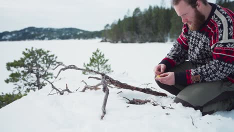 Mann-Mit-Streichhölzern-Verbrennt-Trockenes-Holz-Für-Brennholz-In-Der-Winterlandschaft