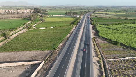 Aerial-shot-of-multi-lane-Peruvian-highway-of-Panamericana-Norte-between-vast-farmlands-on-both-corners