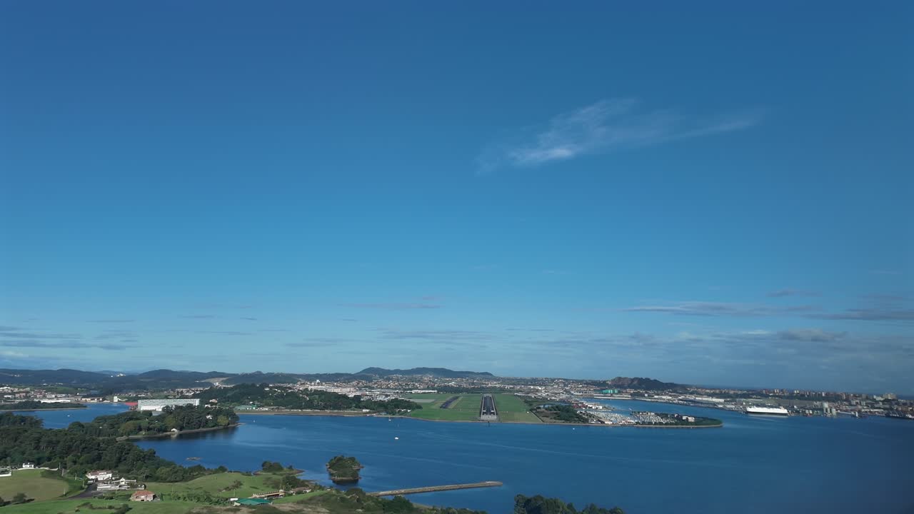 an immersive pilot’s eye view FPV from the cockpit of a jet approaching to Santander airport runway RWY 29, overflying the bay, with a view of the city on the right, in a splendid sunny morning