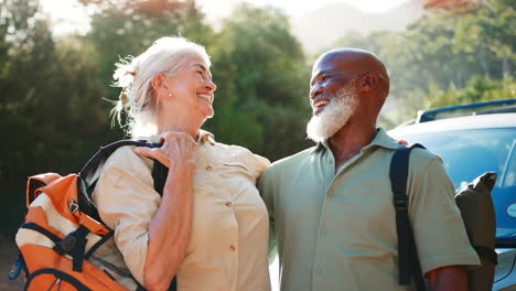 portrait of senior couple going for hike in countryside standing by car together