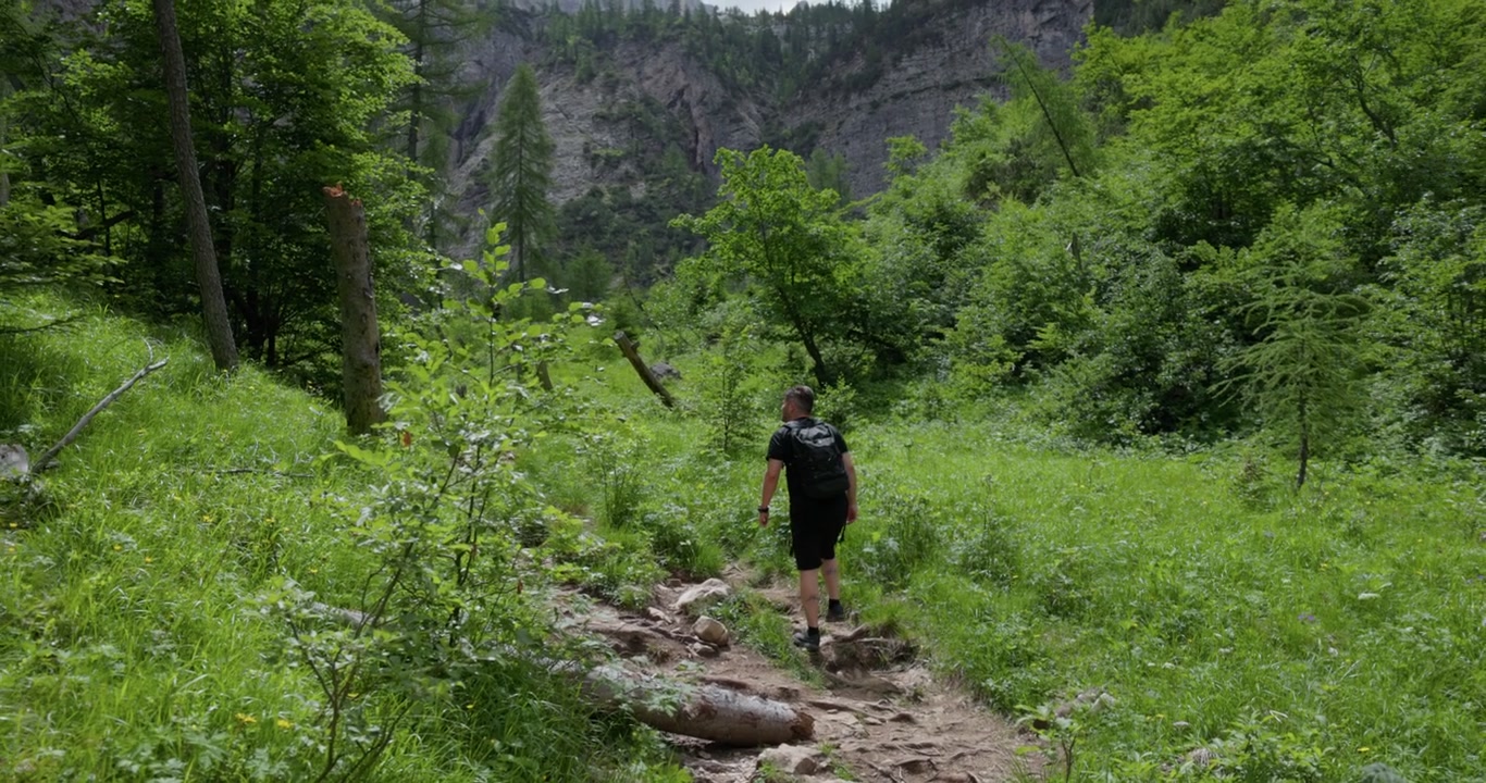 En man med ryggsäck vandrar längs en vandringsled nära Lago di Sorapis i Dolomiternas bergskedja i norra Italien. Slow motion-tagning.