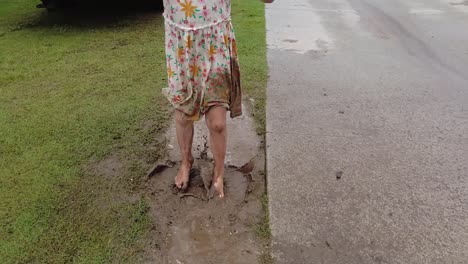 niña joven irreconocible con vestido saltando en charco de barro, cámara lenta