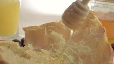 drizzling honey on fresh baked croissant close up shot