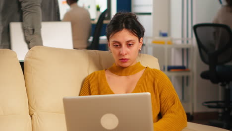 Geschäftsfrau-Sitzt-Auf-Der-Couch,-Hält-Laptop-In-Der-Hand-Und-Lächelt-In-Die-Kamera