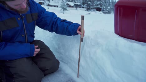 cropped image of a person measuring thickness of snow using folding meter stick in norway