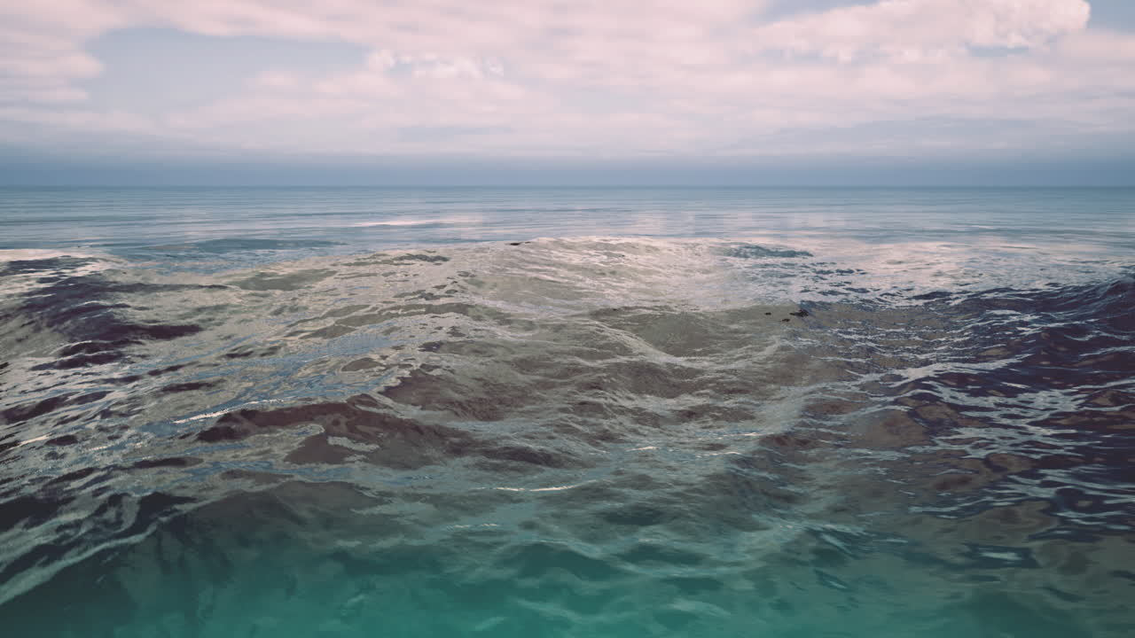 Vaste onde oceaniche riflettono la luce solare soffusa in un ambiente costiero tranquillo