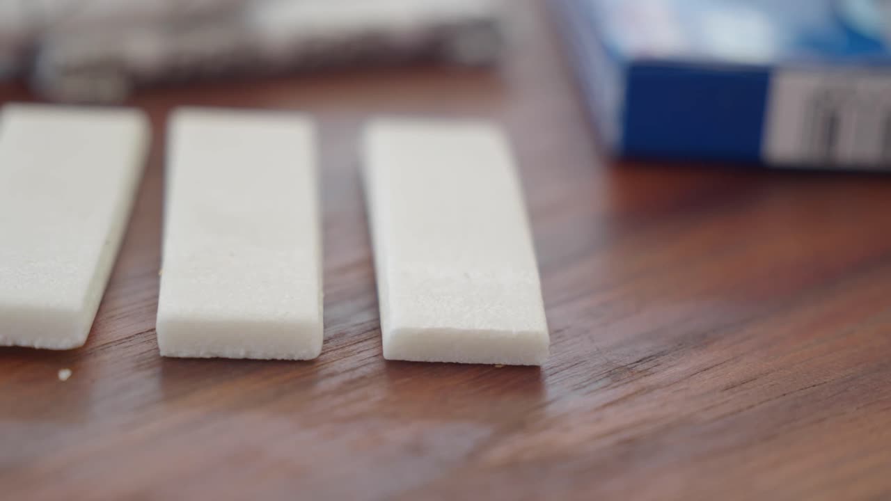 Three pieces of white gum on a wooden surface