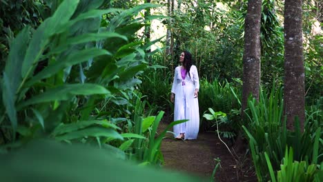 una mujer caminando por el bosque, mirando la exuberante vegetación y las hojas verdes con asombro