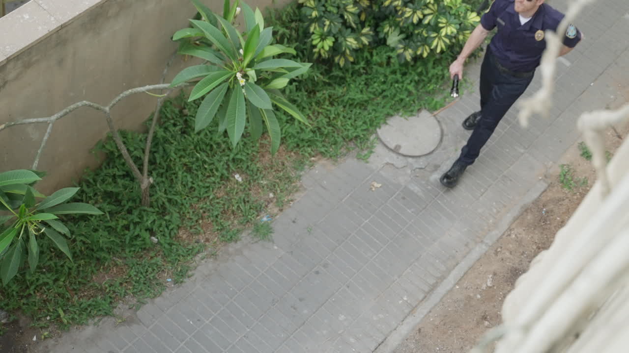 Police officer or security guard patrols outdoor area, speaking into his radio while staying alert. Law enforcement, surveillance, safety, authority. operations, emergency response, and public safety.