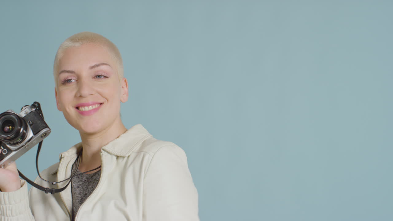modelo caucásica femenina posando con slr vintage contra fondo azul 01