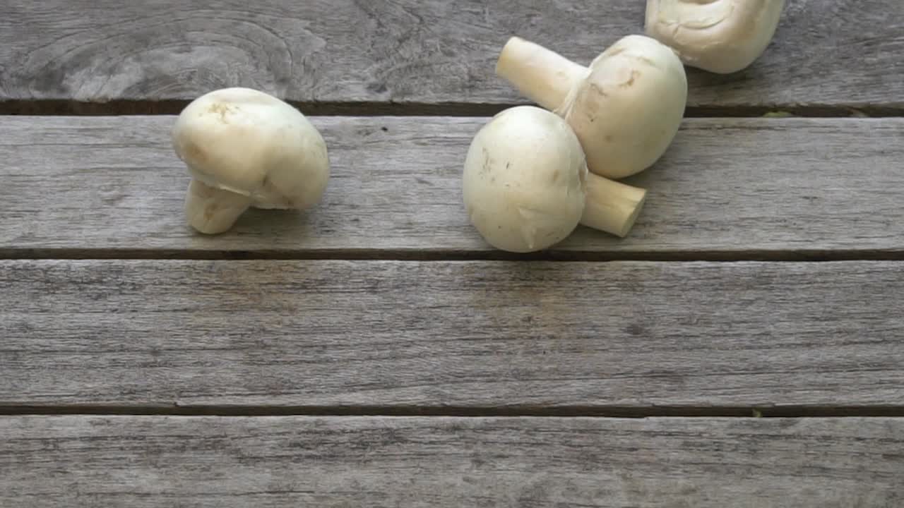 신선한 버섯 다발이 나무 탁자에 떨어지는 영상