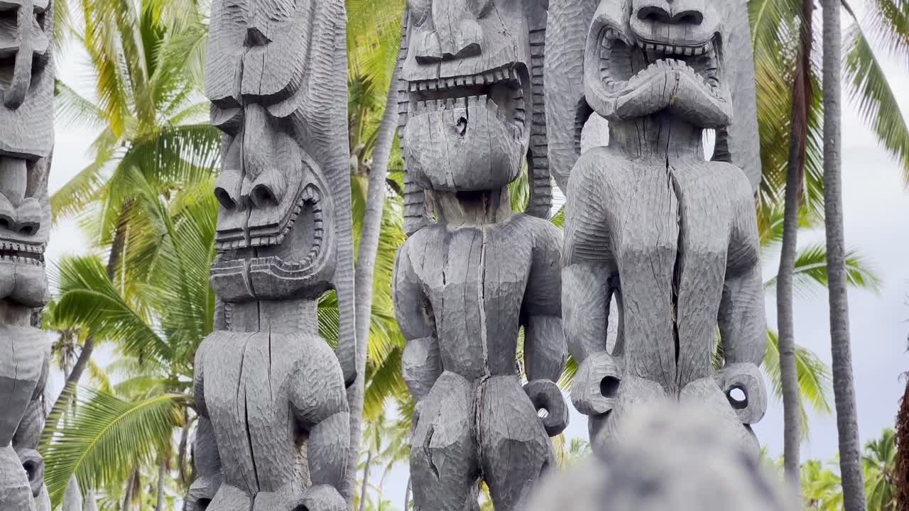 Cinematic close-up panning shot of tiki statues at Pu'uhonua O Honaunau National Historical Park in Hawai'i