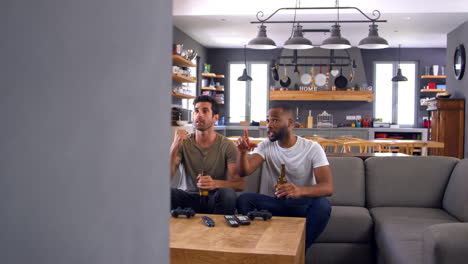 dos amigos hombres se sientan en el sofá y ven deportes en la televisión