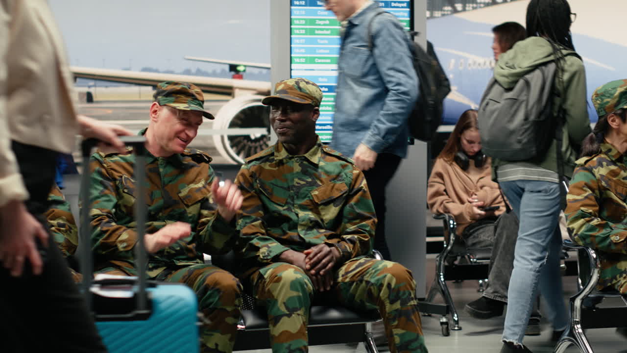 Soldati dell'esercito che chiacchierano e viaggiano, seduti su sedie in aeroporto