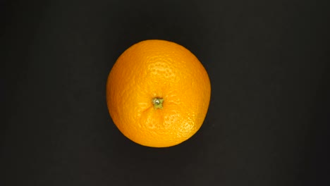 rotación de naranja en un fondo negro aislar. jugos frescos, frutas, vitaminas y concepto de verano.