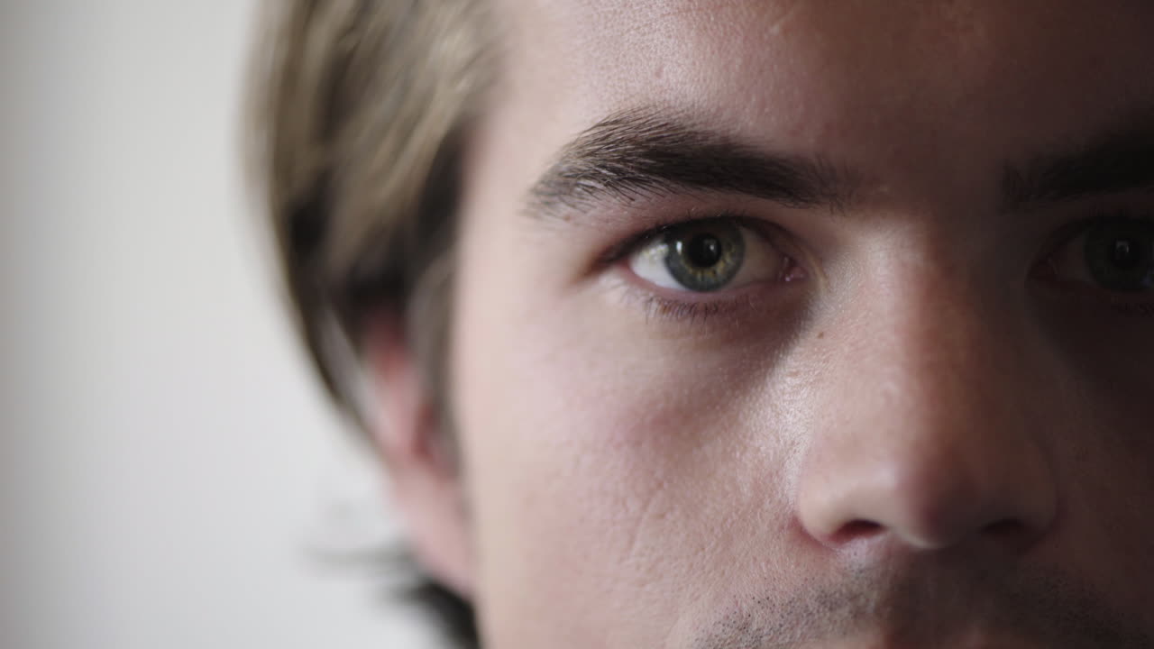 primer plano de un joven caucásico abriendo los ojos buscando una visión seria