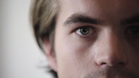 primer plano de un joven caucásico abriendo los ojos buscando una visión seria